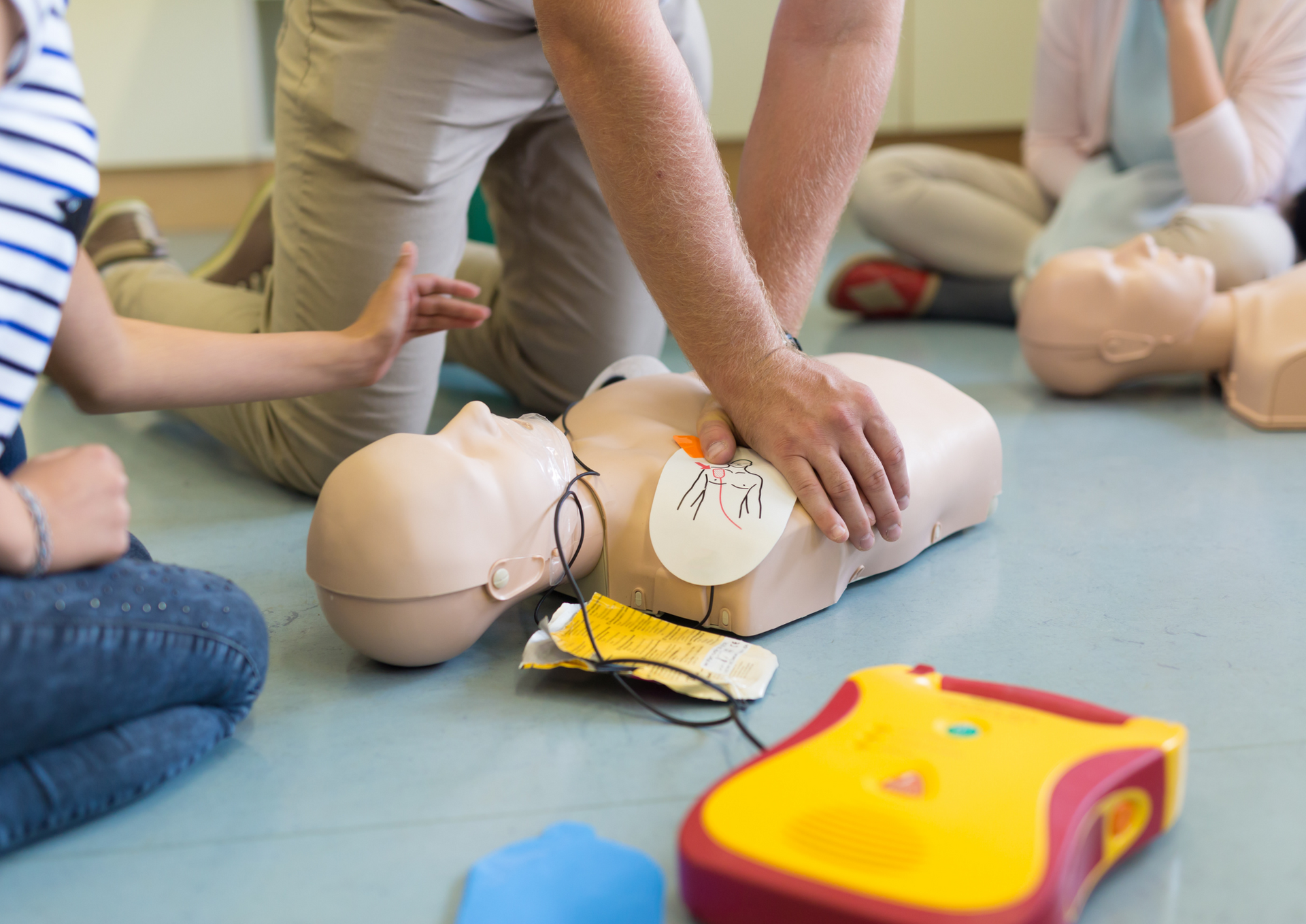 Eine Erste Hilfe Puppe und Personen, die auf der Puppe üben